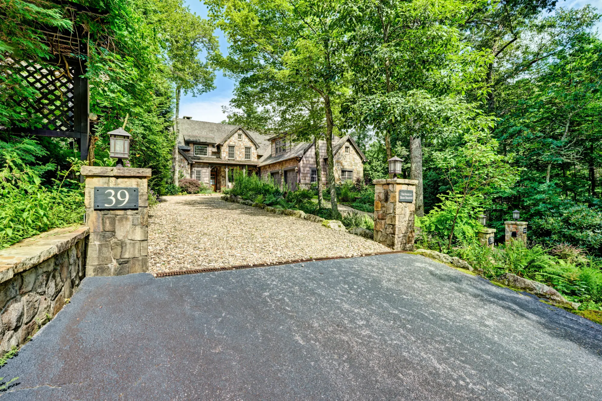 Elegant stone house surrounded by lush greenery and trees.