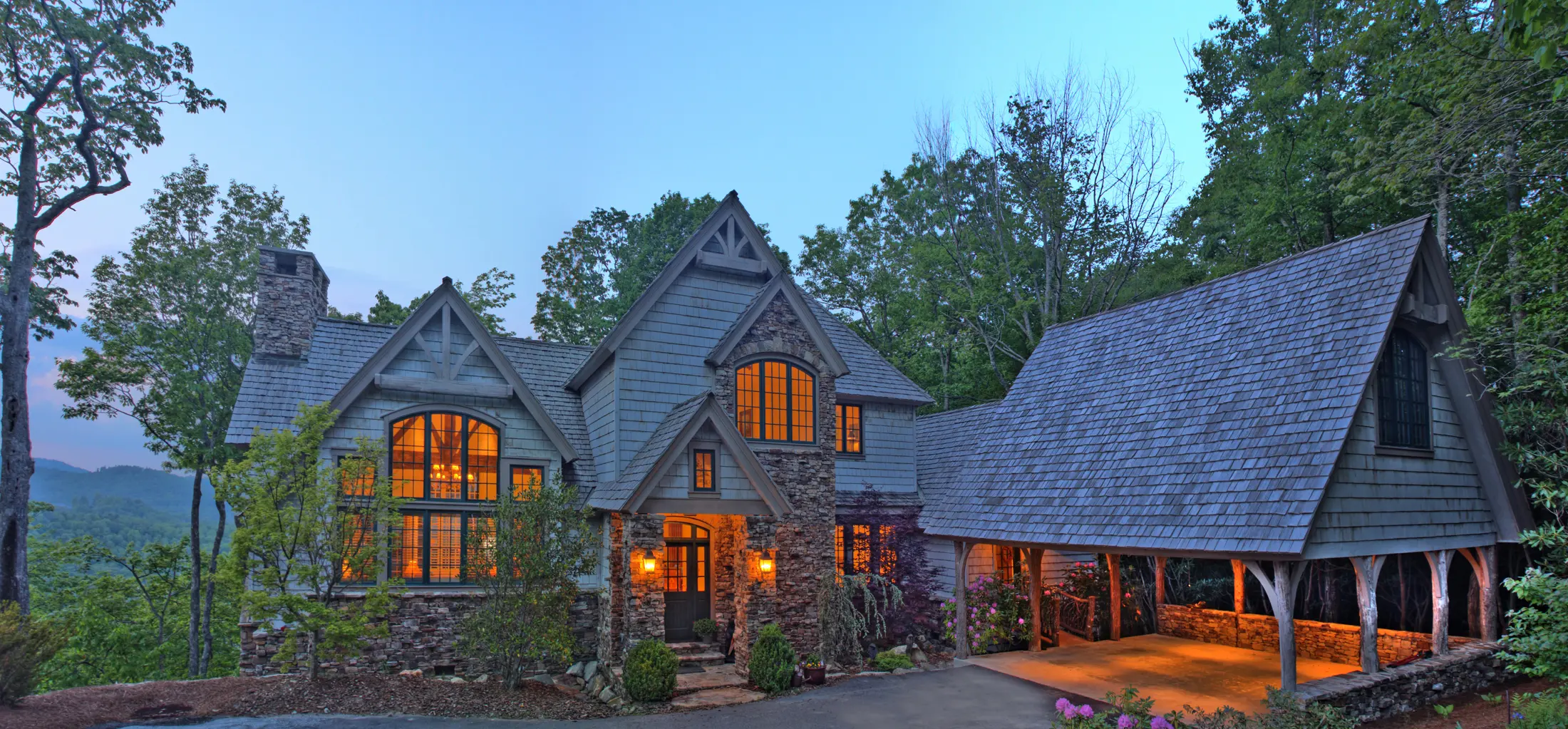 A charming stone cottage with warm glowing windows at dusk.
