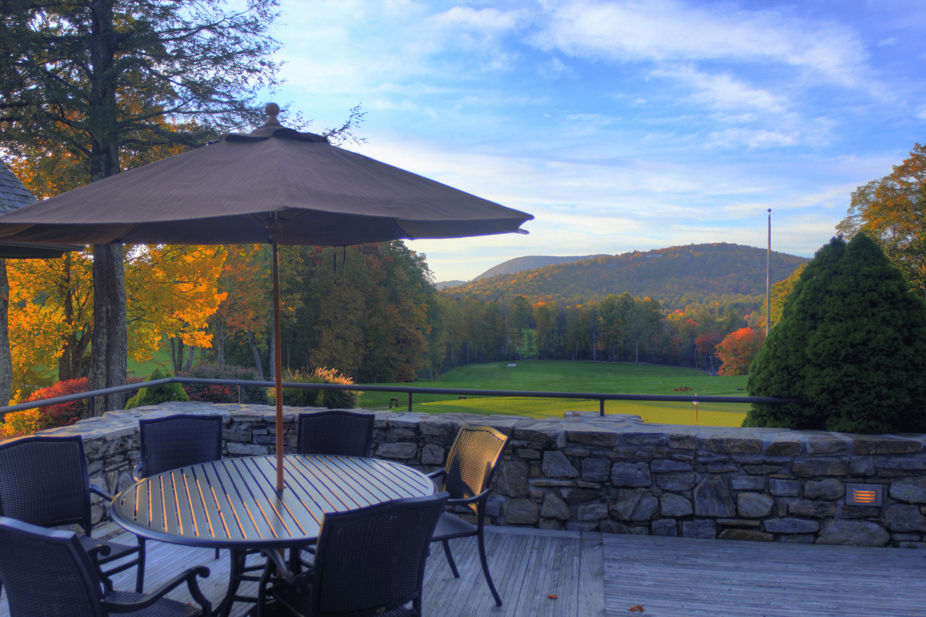 Outdoor patio with seating, umbrella, and scenic mountain view.
