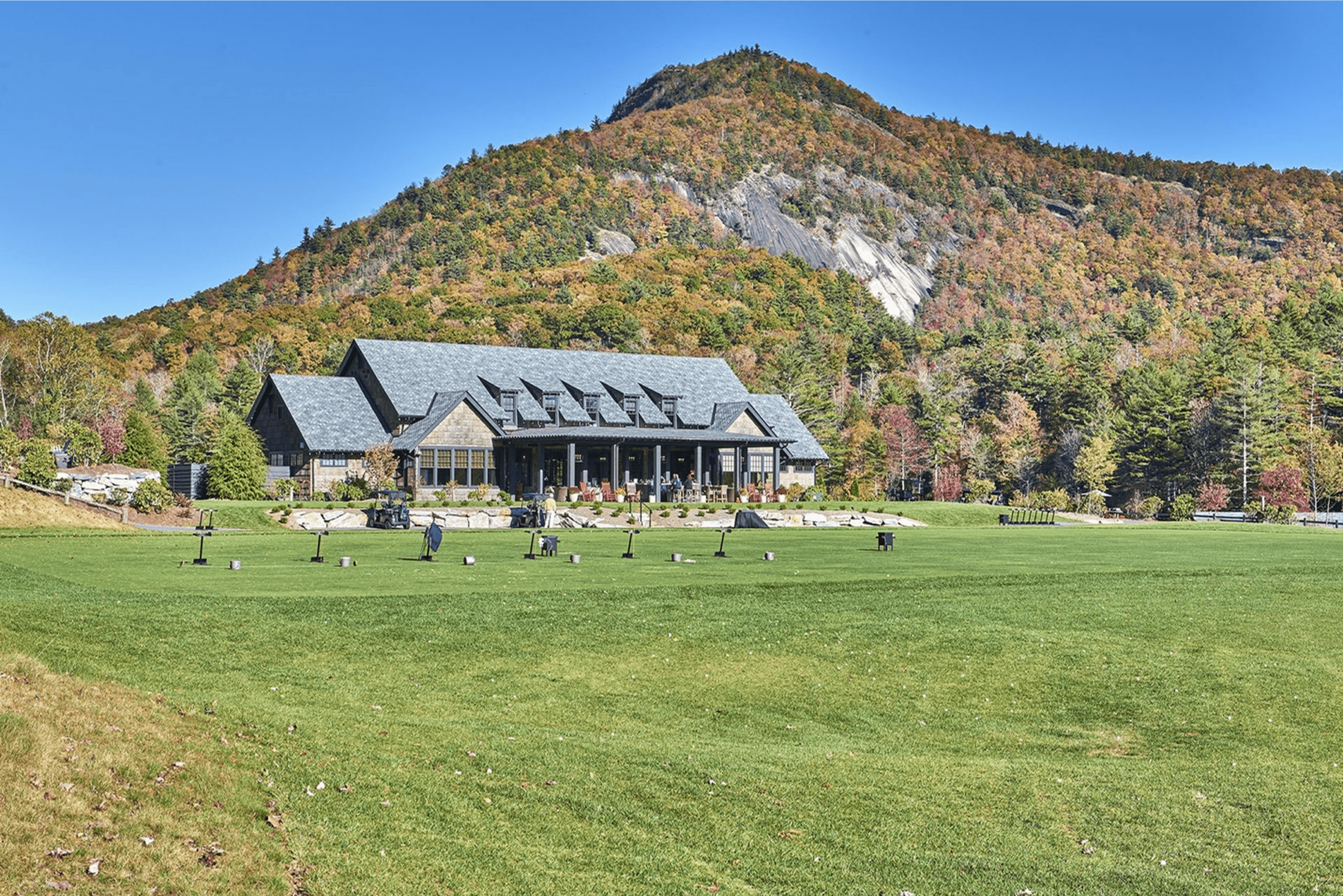 A scenic lodge with mountains and people on a sunny day.