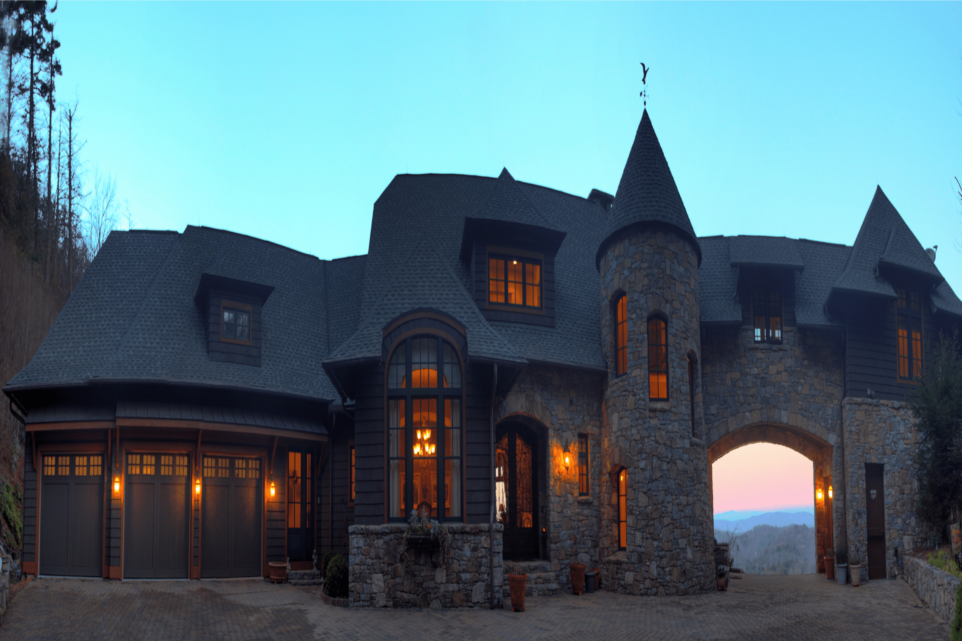 A castle-like house glowing warmly at dusk.