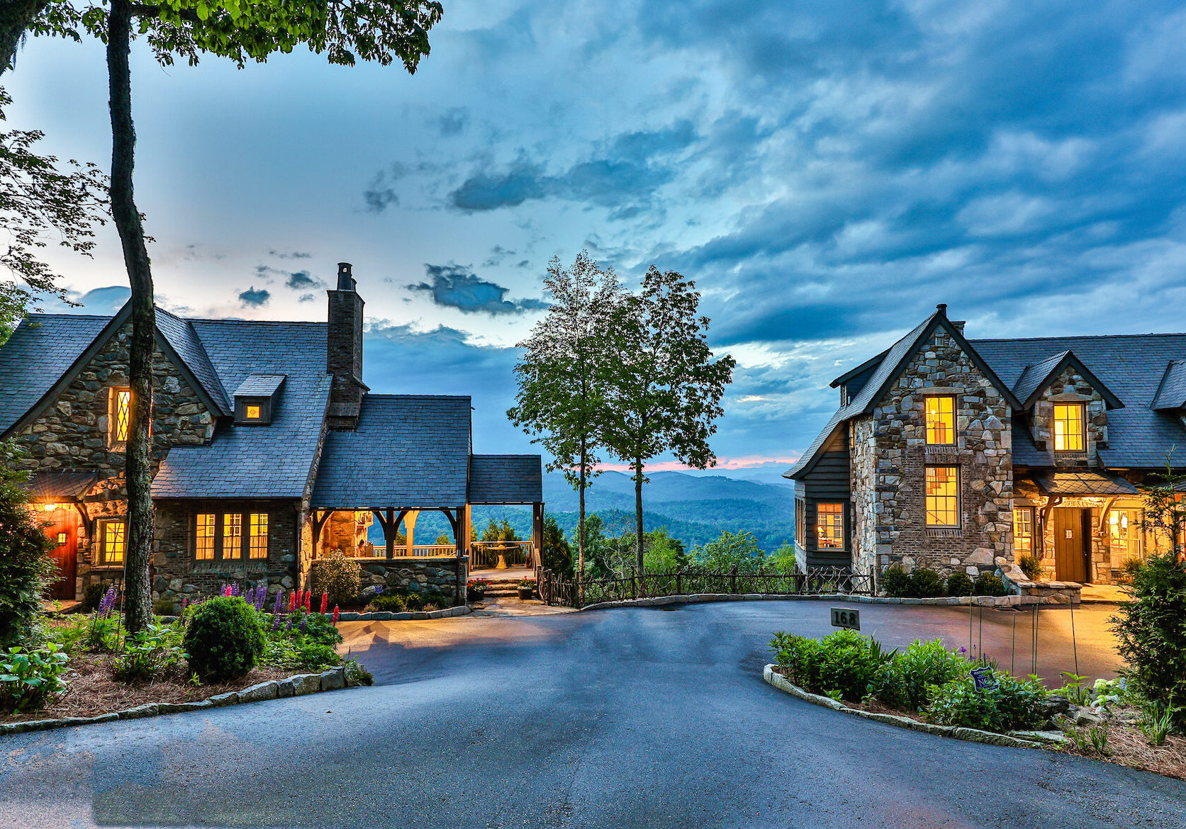 A charming stone house with warm lights under a dramatic evening sky.